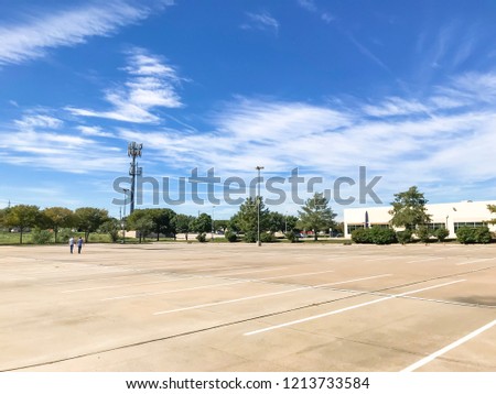 Large empty office parking lots with people walking at business park in America. Cloud blue sky background.