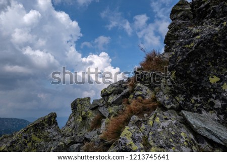 mountain panorama from top of Banikov peak in Slovakian Tatra mountains with rocky landscape and shadows of hikers in bright day with storm clouds approaching