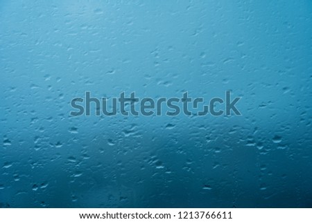 Blurred image of drops of rain on mirror with buildings and road. Using as background.