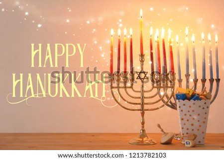 Image of jewish holiday Hanukkah background with traditional spinnig top, menorah (traditional candelabra) and burning candles