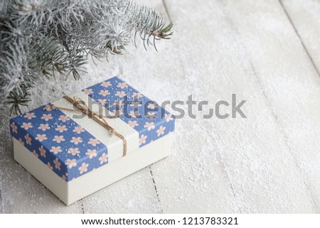 Christmas gift box with festive pattern under snowy fir tree, copy space