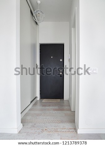 Empty hallway with closed door inside an apartment. White corridor inside an apartment block. Royalty-Free Stock Photo #1213789378