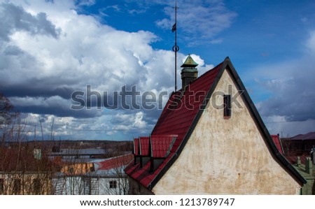 Old stone house with a red roof on a cloudy sky background