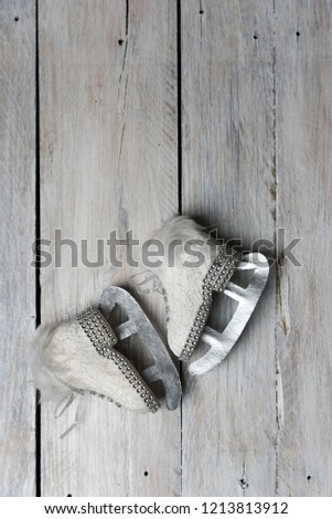 Cute, white Skates with glittering pebbles on a rustic wood background - a winter greeting card background