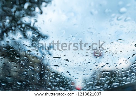Raindrops on the windshield on a rainy day, Miserable rainy day traffic scene through wet window glass. City view