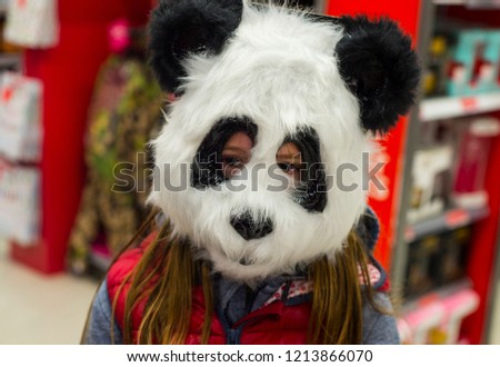 A girl posing with a panda bear mask on