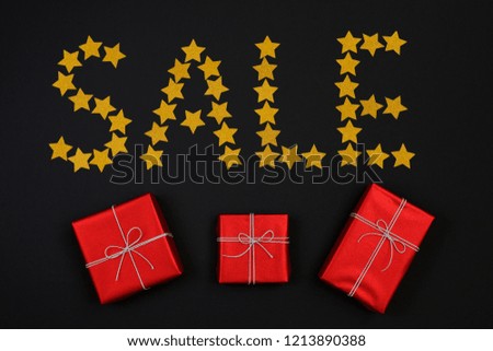 Word sale made from gold star and red gift boxes with presents on black background. Flat lay. Gift box with BLACK FRIDAY SALE. shopping concept.