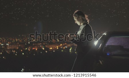 portrait young woman driver stands next to a car night lights of the city