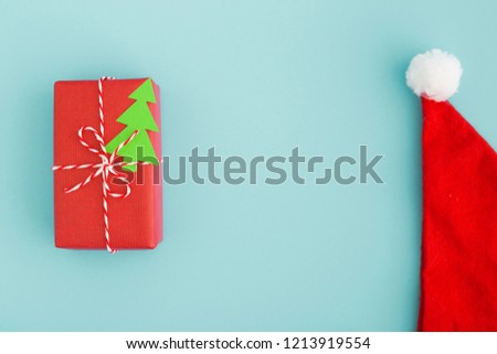 Christmas card with a gift and Santa hat. Xmas holiday concept.