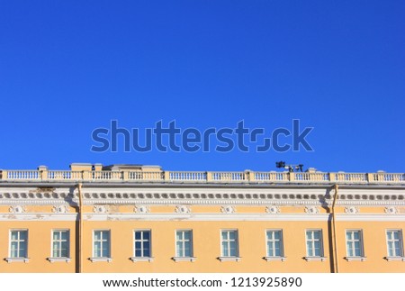 Modern Old Building Classical Architecture. Facade of Old Historical Minimalist House with Yellow Walls. Apartment and Office Building Front with Simple Square Windows in Row on Empty Sky Background