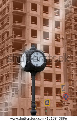 Huge sidewalk clock in front of the building under construction. Time is running out. Time of construction is over. Concept of deadline. Vertical format