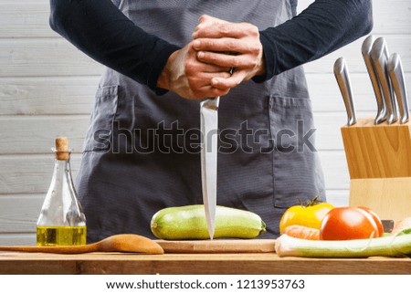 Top view woman's hands cutting cheese on wooden cutting board on wooden table with grapes and dried fruits, nuts, pumpkin seeds on wooden cheese plate on wooden table with strip tablecloth. Lay flat