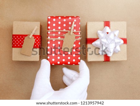 Three Simple Wrapped Present on a Matching Background with Santa's Hand