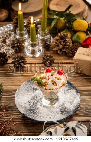 Delicious Vanilla ice cream with red cherry and walnuts in sundae dish cup on christmas decorated background. Studio shot