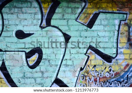 Fragment of graffiti drawings. The old wall decorated with paint stains in the style of street art culture. Colored background texture.
