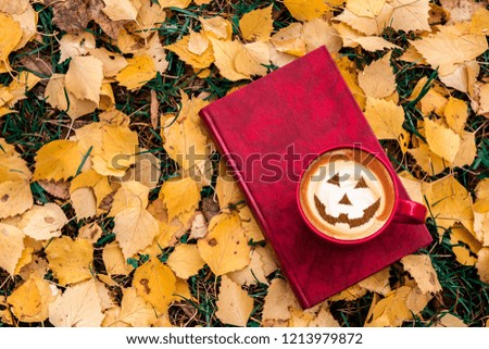 coffee on autumn leaves with halloween symbol