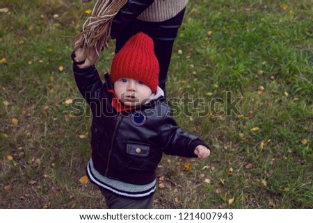 mom and son in leather jackets walking on the field with dry grass autumn
