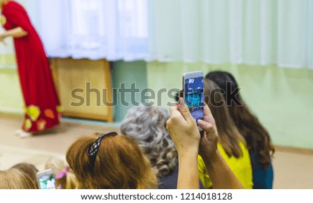 woman taking a picture of children on the phone in kindergarten