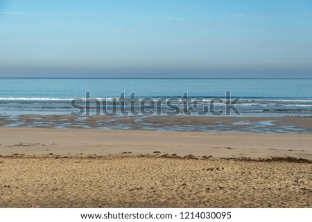 parallel horizontal stripes of the sky, water and beach shot in the morning