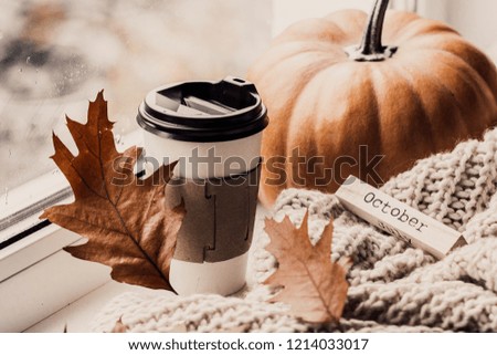 Cup of coffee, pumpkin, dried autumn leaves on window. Autumn composition. 