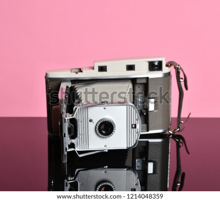 Antique old portable photo camera medium frame on light pink background