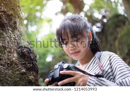 Asian photographer photoshoot working camera. Woman taking photo with smiling for hobby and lifestyle with green trees in forest at outdoor.