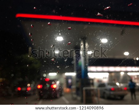 Blurred image, Raindrops on car windshield. Customers who use services in the petroleum station at night. Colorful bokeh and Dark background.