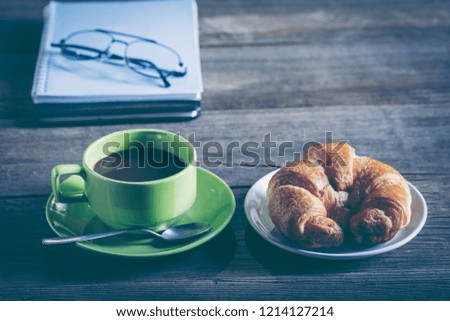 Business breakfast, coffee and croissants, on a wooden surface. Free space for text.