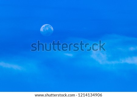 Low contrast waxing gibbous earth moon over the blue winter sky. Soft contrast of white cirrostratus cloud at lower edge of picture.