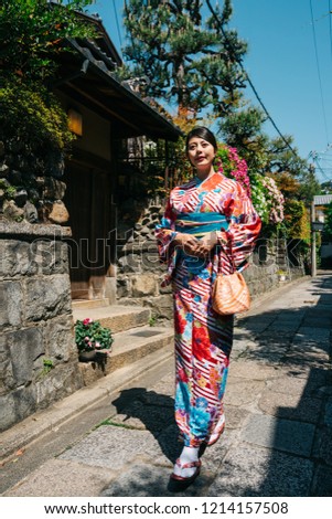 full length of elegant Japanese lady wearing colorful kimono leaving home and going to the temple for blessing. young girl walking on street in Kyoto. Asian girl holiday lifestyle.