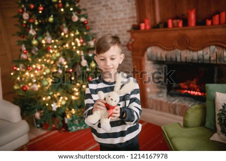 boy sitting near the christmas tree with a book and smiling