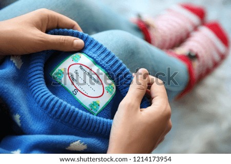 Woman holding Christmas sweater with tag, closeup
