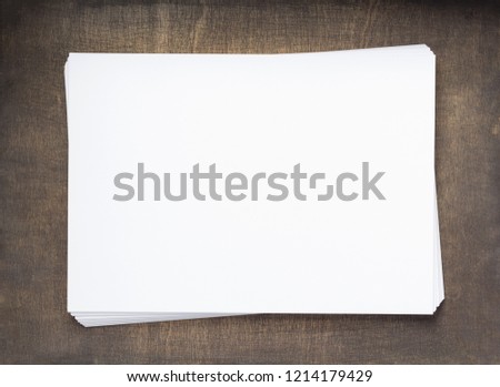stack of paper with empty pages on wooden background, top view