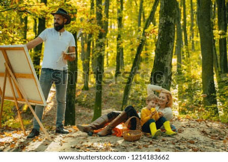 Happy Family vacation in the autumn Park. Father draws picture on nature. Happy family concept. Autumn camping with kids, mother and father