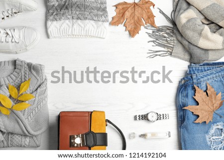 Stylish outfit and autumn leaves on white wooden background, flat lay with space for text. Trendy warm clothes