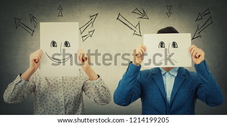 Businessman and businesswoman covering their faces using sheets with drawn happy and sad emoticons, like a mask to hide her real emotion from society. Fake identity concept. Introvert vs extrovert. Royalty-Free Stock Photo #1214199205