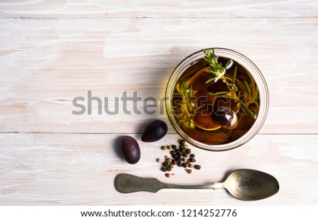 Olives in oil and rosemary on a wooden table top view