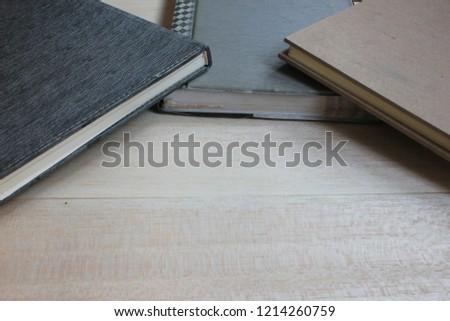 Notebooks are placed over each other on a wooden background.