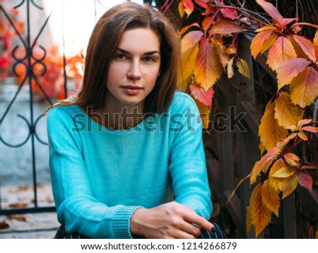 Portrait of a young beautiful woman. The girl on the background of golden autumn, calm and beautiful