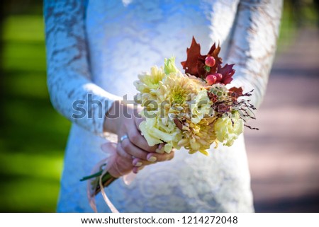 Bride holding colorful elegant modern autumn wedding bouquet in red, marsala, burgundy for a fall wedding.