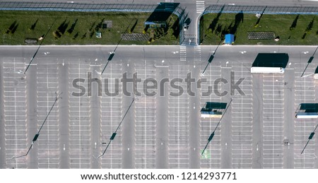 Aerial view from the drone of a truck in an empty parking lot next to a green lawn. Reflection of shadows from street lamps on the asphalt. Top view