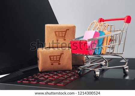 online shopping / e-commerce sale and delivery service concept, discounts, black Friday, sale: shopping cart multicolored packages and boxes with trolleybus logo on laptop keyboard