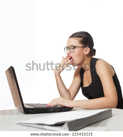 short straight haired young businesswoman yawning on her desk while using laptop.isolated on white