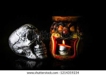 Halloween dark scary horror story ideas concept with joker candle light pot and silver skull human isolated on black background