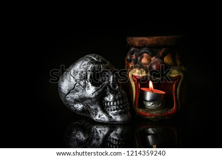 Halloween dark scary horror story ideas concept with joker candle light pot and silver skull human isolated on black background