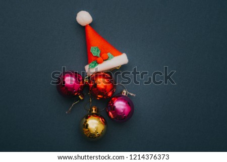 Christmas ornament balls and santa hat on grey background.