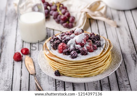 Homemade crepes with frozen berries, topped sugar, rustic wood board, vintage photography