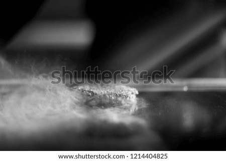 Fresh meat cutlets in a frying pan grill. A lot of steam or smoke. Black and white photo
