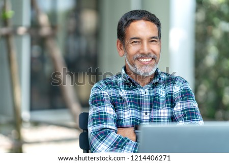 Portrait of happy mature man with white, grey stylish short beard looking at camera outdoor. Casual lifestyle of retired hispanic people or adult asian man smile with confident at coffee shop cafe. Royalty-Free Stock Photo #1214406271