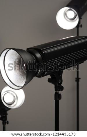 Group of professional black studio illuminators on a grey background. Photo studio equipment concept
